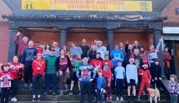 A crowd of people in christmas costumes stood outside Levenshulme Boxing Club before taking part on a Santa Run.