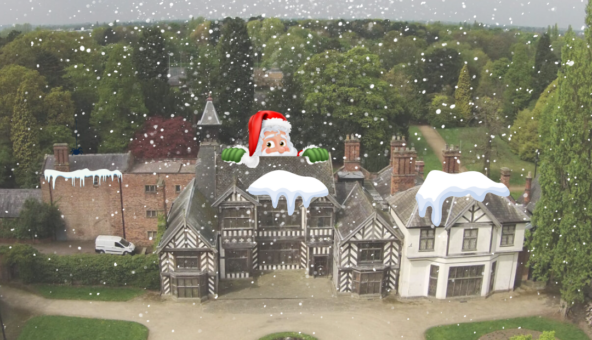 The exterior of Wythenshawe Hall on a snowy day, with snow on the rooftops and snow falling from the sky.