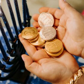 A small pair of hands holding gold foil covered chocolate coins.