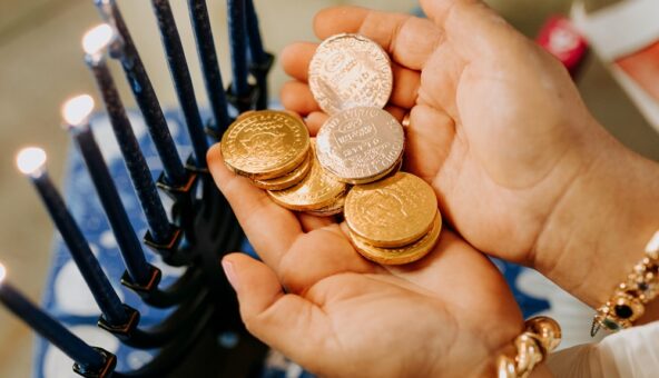 A small pair of hands holding gold foil covered chocolate coins.