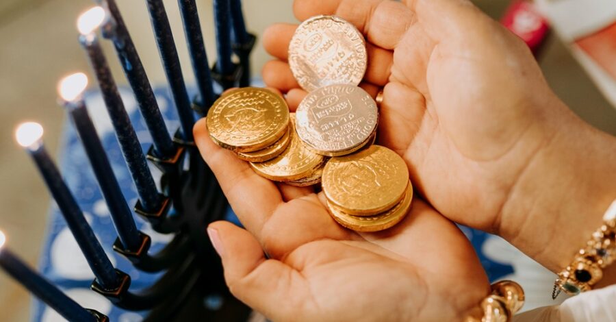 A small pair of hands holding gold foil covered chocolate coins.