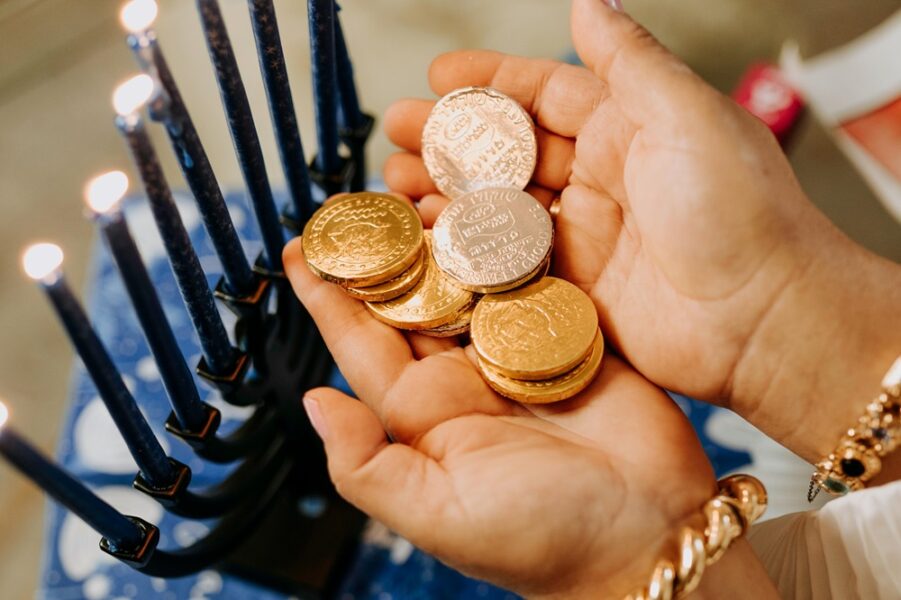 A small pair of hands holding gold foil covered chocolate coins.