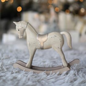 A small white wooden rocking horse with a gold saddle. The toy is placed on a fluffy grey carpet.