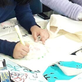 A close-up of a pair of hands decorating a tote bag.