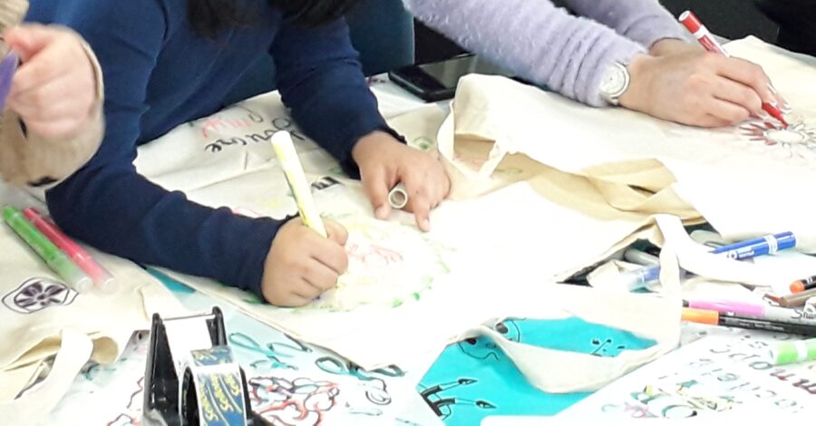 A close-up of a pair of hands decorating a tote bag.