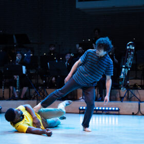 Two dancers and an orchestra on stage.