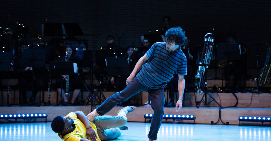 Two dancers and an orchestra on stage.