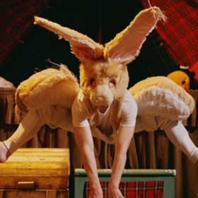 A dancer costumed as a rabbit leaps in the air