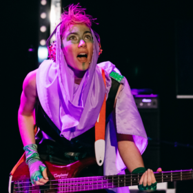 A musician playing an electric guitar in punk make-up