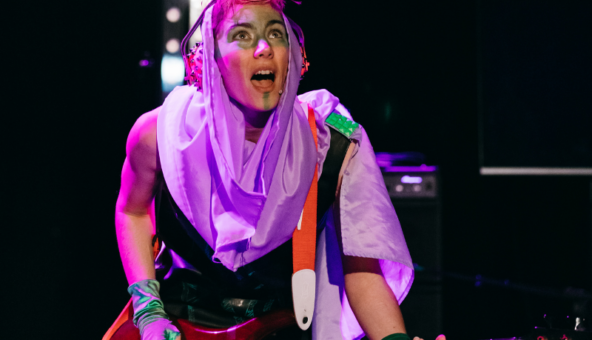 A musician playing an electric guitar in punk make-up