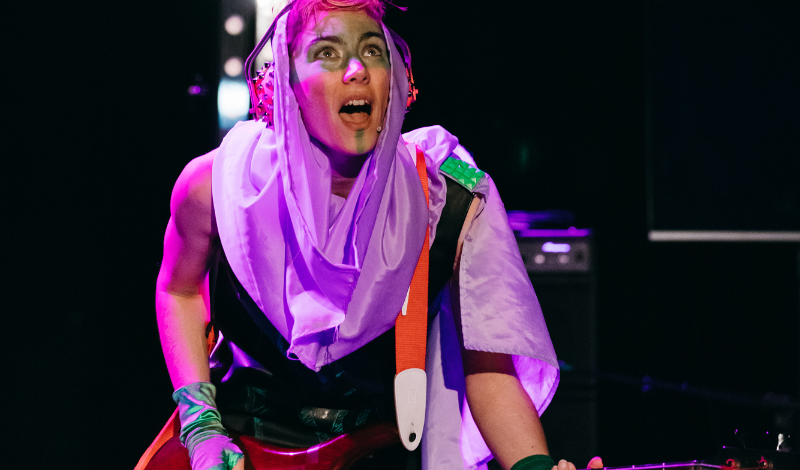 A musician playing an electric guitar in punk make-up