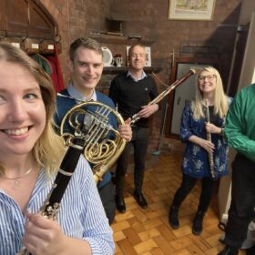 The Northerly Winds musical quintet holding their instruments and smiling.