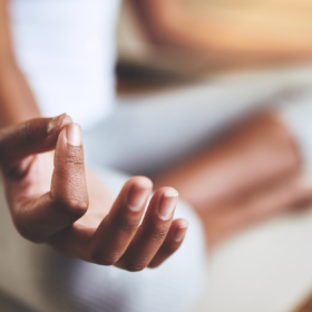 Woman sat with her legs crossed with her hand in a meditative pose.