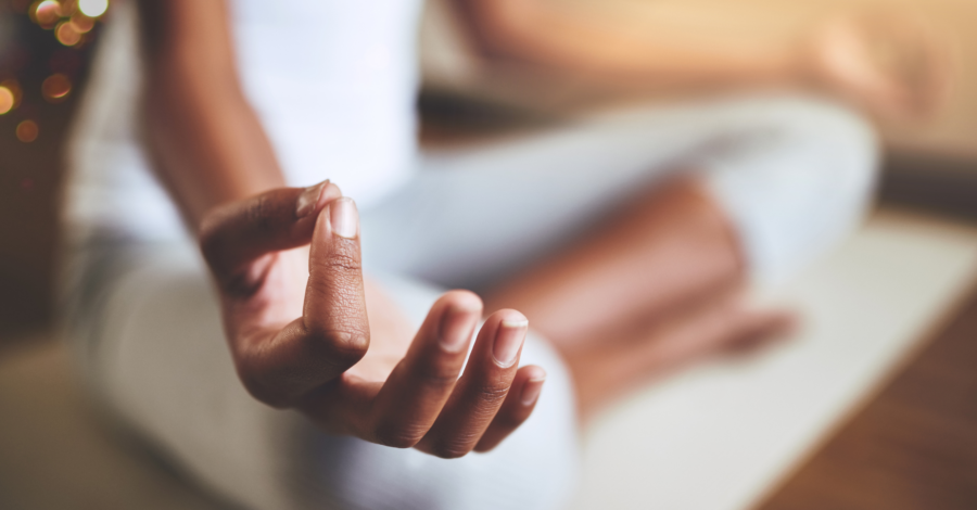 Woman sat with her legs crossed with her hand in a meditative pose.