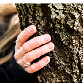 A Woman's hand touching the bark of a tree.