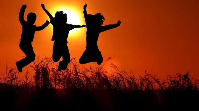3 young people in silhouette jumping in front of a red sunset