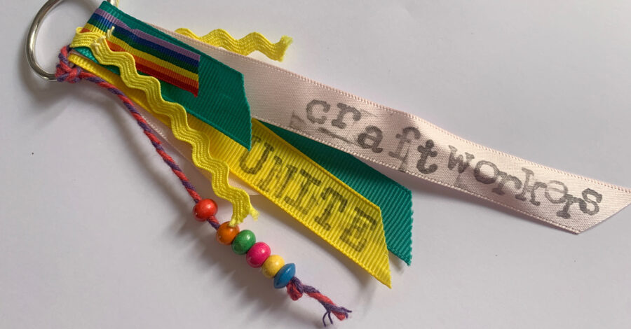 A set of ribbons on a keyring - one has coloured beads on it, another is printed with the word unite and another has the writing craftwork.