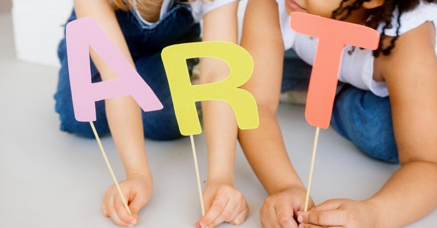 Children holding letters on sticks spelling out ART.