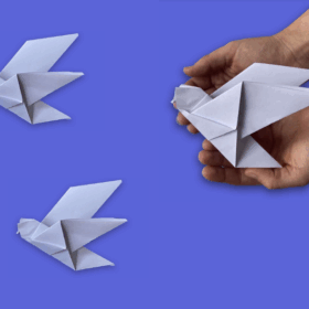 Hands holding a white paper origami dove.