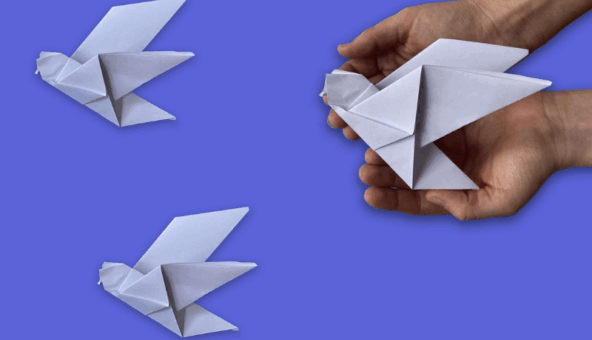 Hands holding a white paper origami dove.