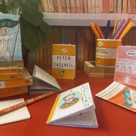 A display of mini paperback books and pencils.