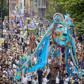 A huge crowd surrounding a large blue puppet head