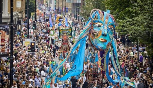 A huge crowd surrounding a large blue puppet head