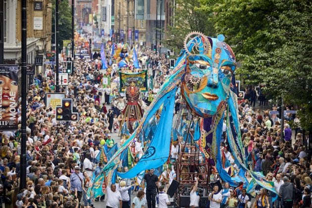 A huge crowd surrounding a large blue puppet head