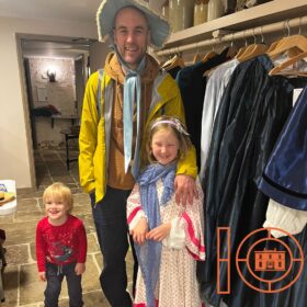 An adult and two small children dressed up as Victorians.
