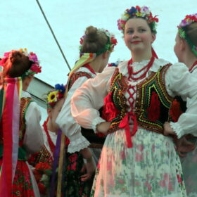 Four young female dancers in folk costumes, one looking at the camera