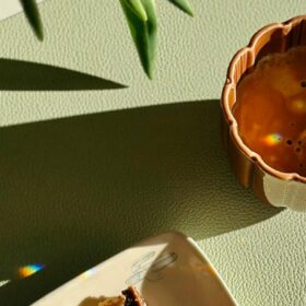 A cup of chai with a long shadow and piece of cake