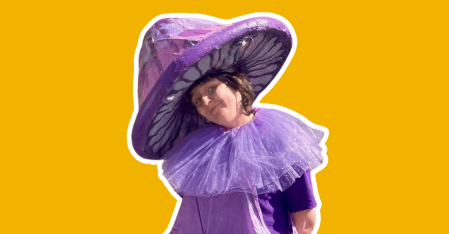 A performer dressed as a giant purple mushroom, with a purple hat and a purple ruff.