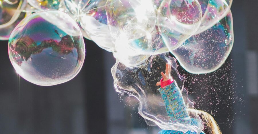 A girl in a blue cardigan creating a huge string of bubbles
