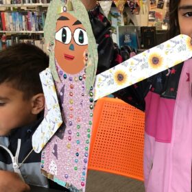 A child holding a handmade puppet crafted from paper.