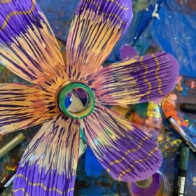 A flower that has been crafted from a recycled bottle, paper and paint.