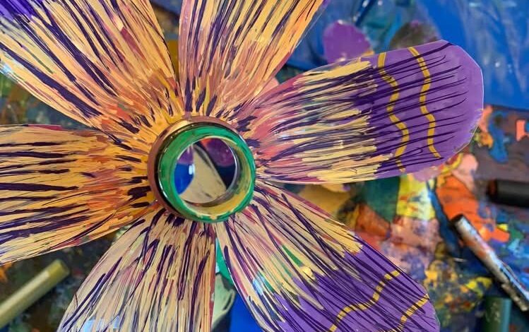 A flower that has been crafted from a recycled bottle, paper and paint.