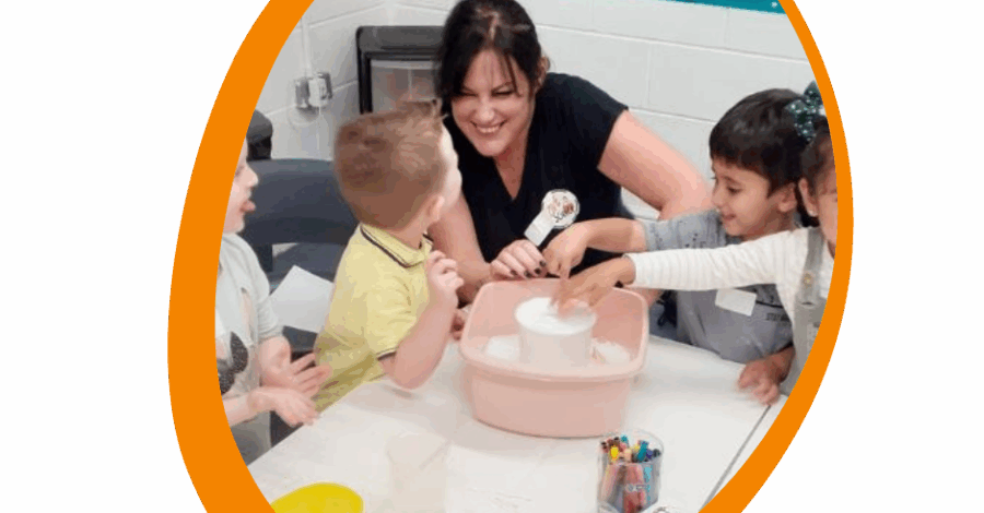 An adult sat at a table with two children doing an activity.