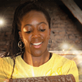 Alicia opening a wooden chest out of which light comes.