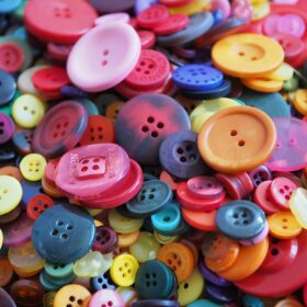 A close up of a pile of different coloured and different size buttons.