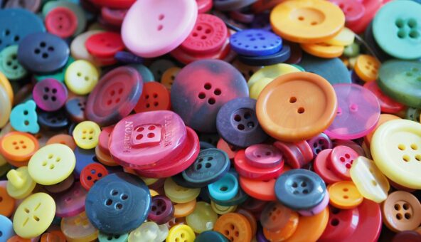 A close up of a pile of different coloured and different size buttons.