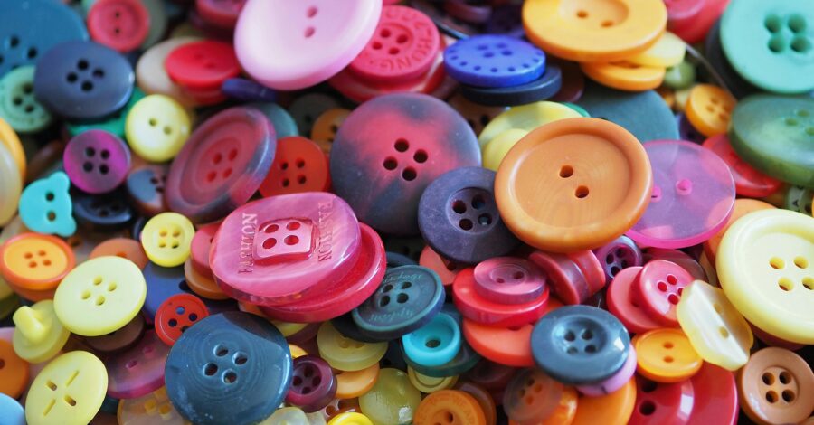 A close up of a pile of different coloured and different size buttons.