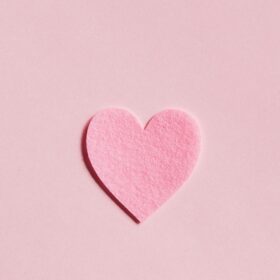 A pink felt heart on a pink background.