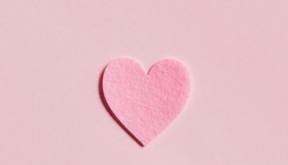 A pink felt heart on a pink background.
