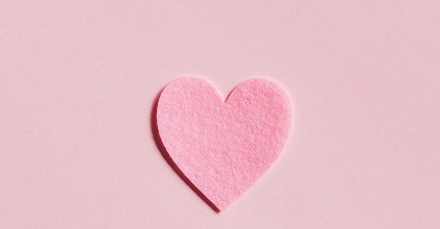 A pink felt heart on a pink background.