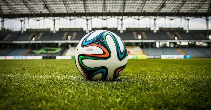 Brightly coloured football on grass in a large stadium