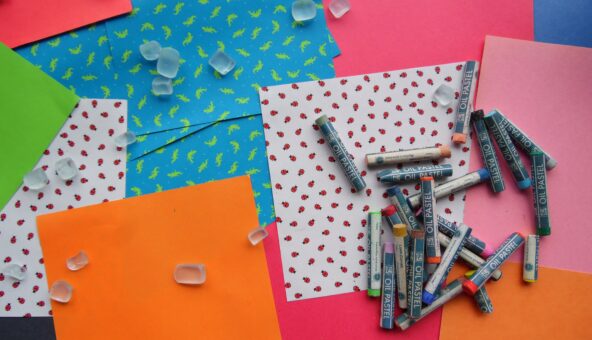 Some coloured paper and crafting supplies including crayons.