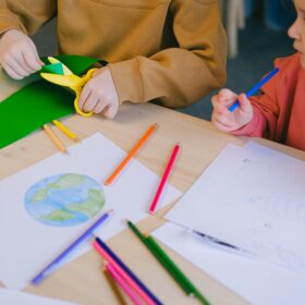 Children sat at a table, taking part in craft activities like colouring in and cutting paper.
