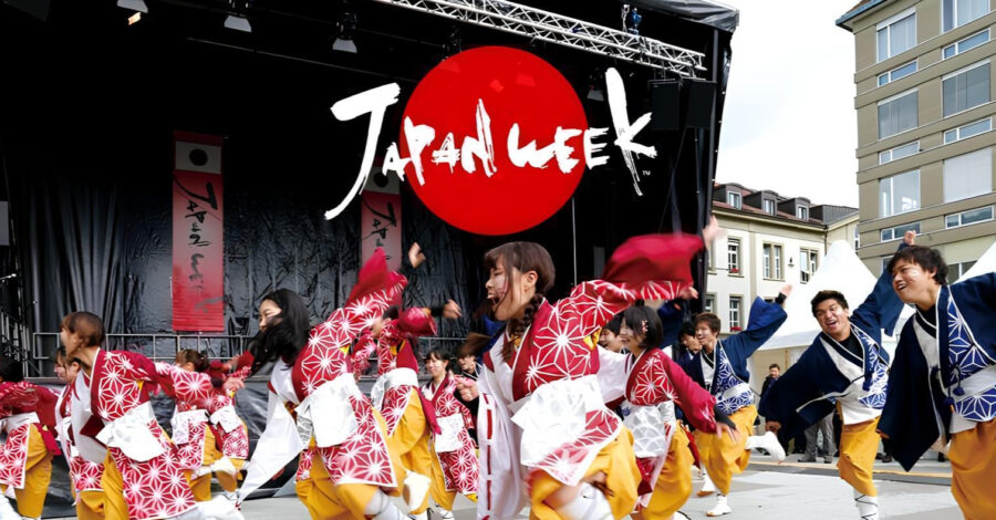 Japanese dancers performing on a stage with a backdrop that reads 'Japan Week'.