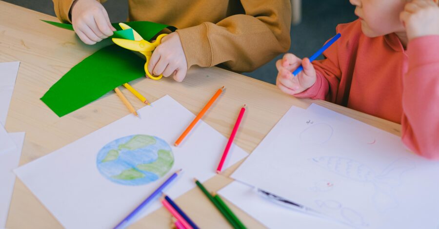 Children taking part in a craft activity that involves colouring in and cutting paper.
