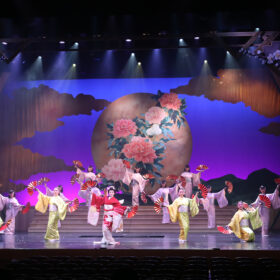 Performers in traditional Japanese dress on a large stage.